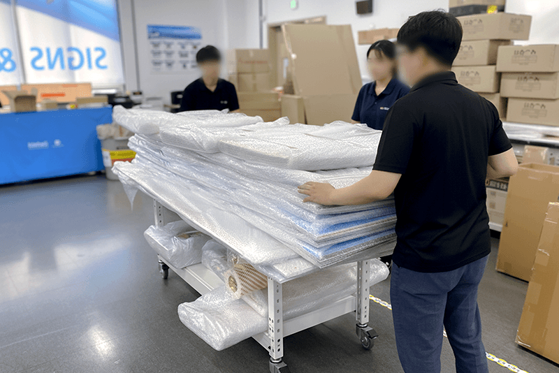 5_센터네트워크_18_직원들이 완충 포장된 인쇄물을 확인하고 출하 준비를 진행하는 킨코스 작업 현장