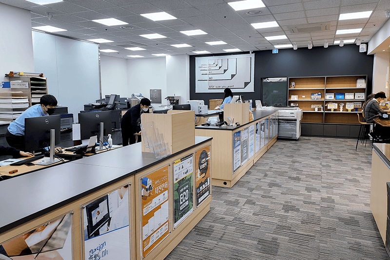 5_센터네트워크_7_킨코스 센터 매장 내부 전경, 직원들이 고객 주문을 처리하고 인쇄 장비를 운영하는 모습