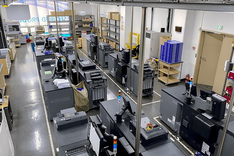 5_센터네트워크_8_킨코스 보안 제작 지원 센터 내부 전경, 다수의 인쇄 장비가 정렬된 생산 라인 환경