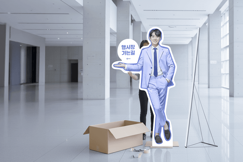 2_포장배송_16_킨코스에서 제작한 행사 안내 스탠드를 전시장 입구에 설치하고 있는 장면, 납품 후 현장 설치 지원 예시