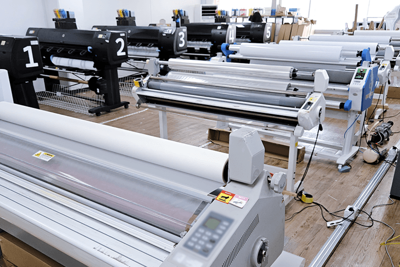 1_생산제작_12_대형 실사 출력기와 라미네이팅 장비가 정렬된 킨코스 실사 인쇄 존, 출력 후 후가공 공정까지 이어지는 장비 배치 모습