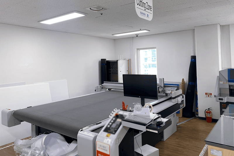 1_생산제작_13_킨코스 Cutting Zone 내부, 대형 커팅 장비가 설치된 공간에서 인쇄물 절단 및 재단 작업이 이루어지는 장면