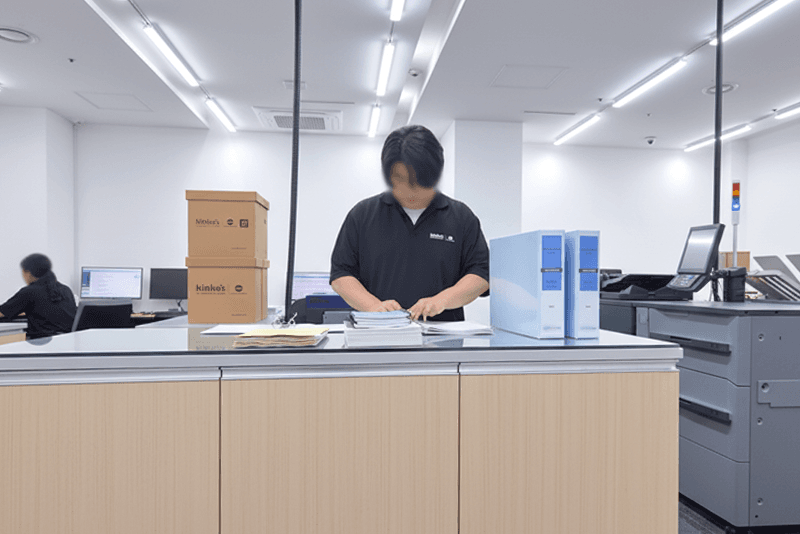1_생산제작_8_킨코스 직원이 제본된 인쇄물을 검수하고 정리하는 모습, 맞춤 제작물의 품질 확인 및 포장 전 공정 관리 장면
